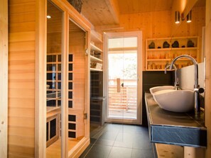 A wooden interior with a bathroom featuring a large sink and a glass door leading to an outdoor area. - # 6 mit IR-Sauna und Sprudelwanne Innen by Interhome (Turracher Höhe)