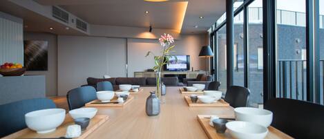A modern dining area with a long table set for a meal, surrounded by comfortable seating.