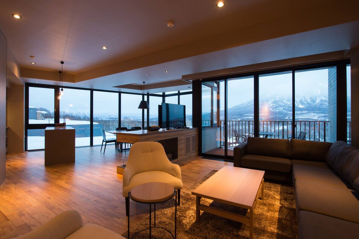 Un amplio salón con un ventanal, un sofá, una mesa de centro y un televisor.
