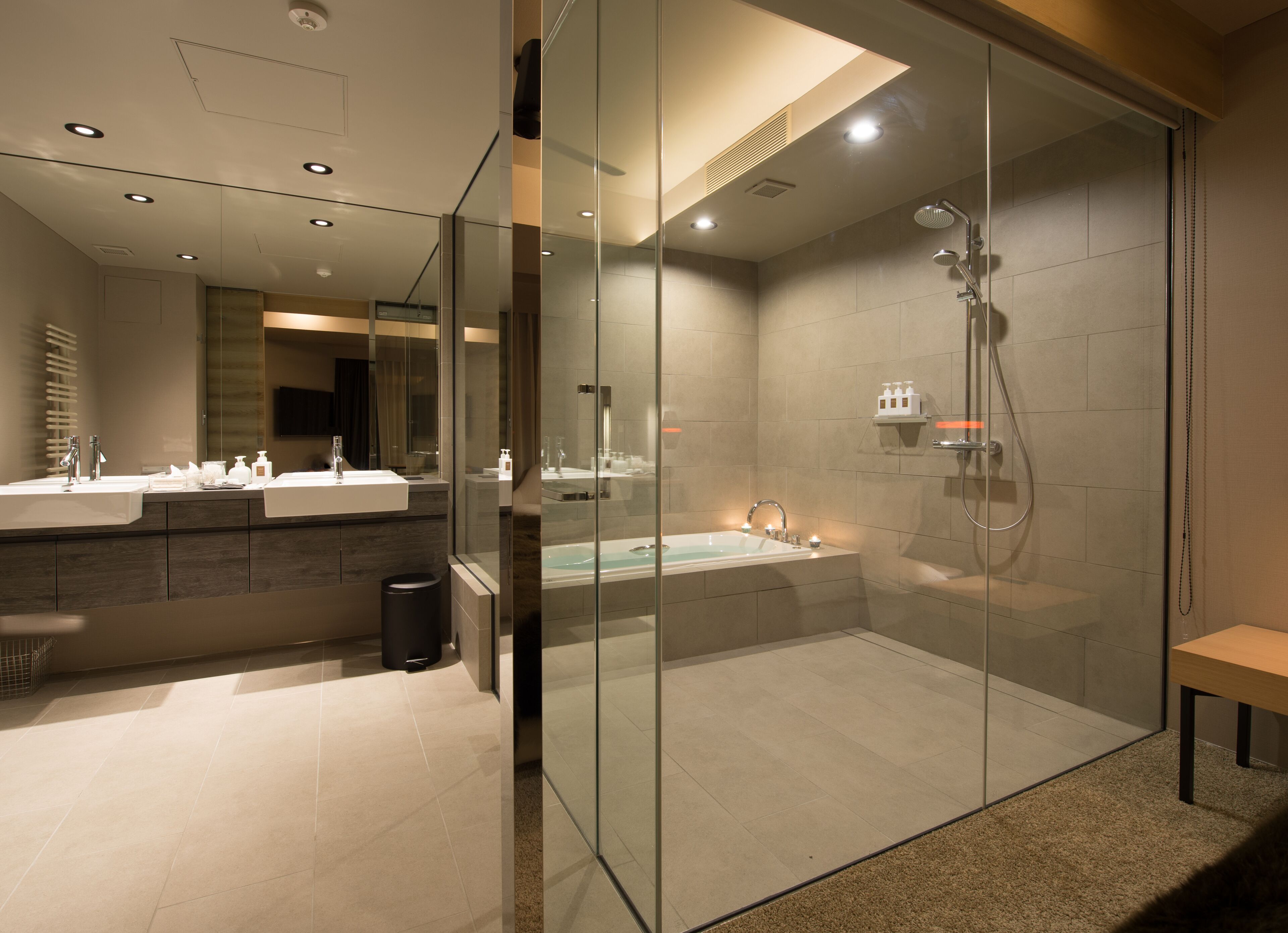 A modern bathroom with a glass-enclosed shower, a bathtub, and a vanity with dual sinks.