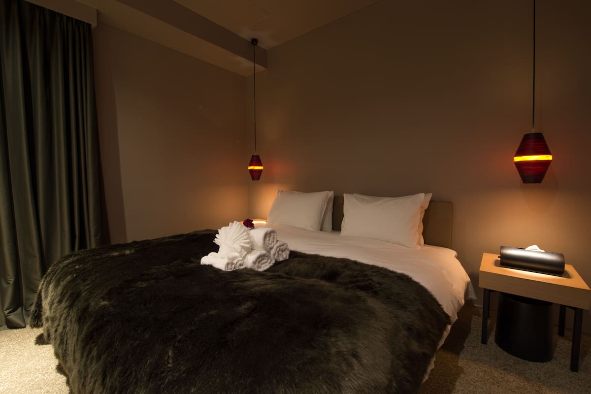 Una habitación de hotel con una cama grande, dos mesitas de noche y una lámpara.