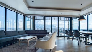 A spacious living area with a large sofa, a coffee table, and a dining table with chairs. - Aspect Luxury Apartments by H2 Life (Kutchan)