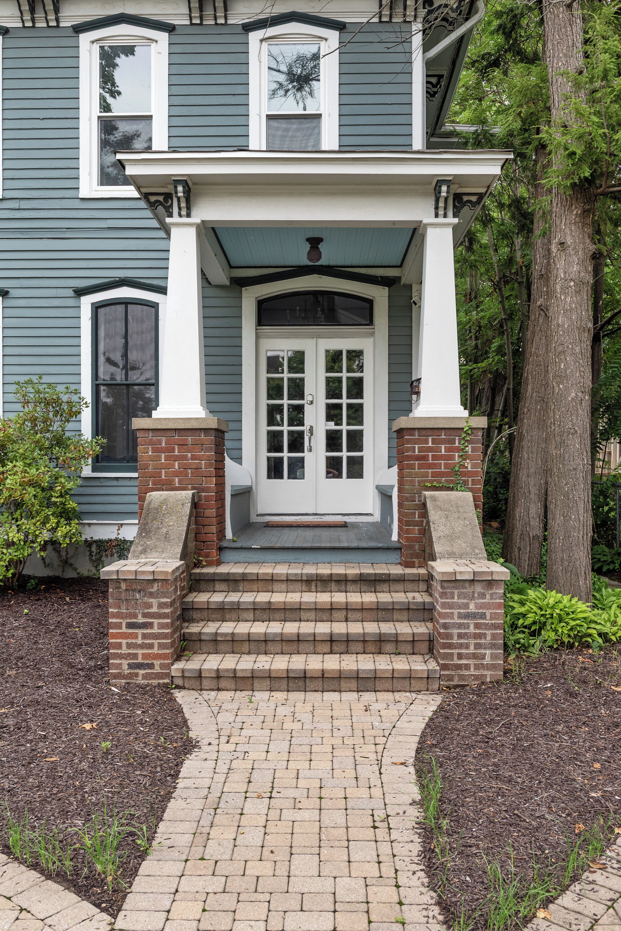 A two-story house with a front porch, a brick chimney, and a mailbox.