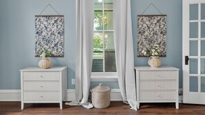 A room with two white cabinets, each with a hanging floral tapestry and a vase with flowers. - Victorian · Game Room · Walk to Beach + Downtown (Lake Geneva)