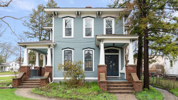 A two-story house with a front porch, brick steps, and a small garden area. - Victorian · Game Room · Walk to Beach + Downtown (Lake Geneva)