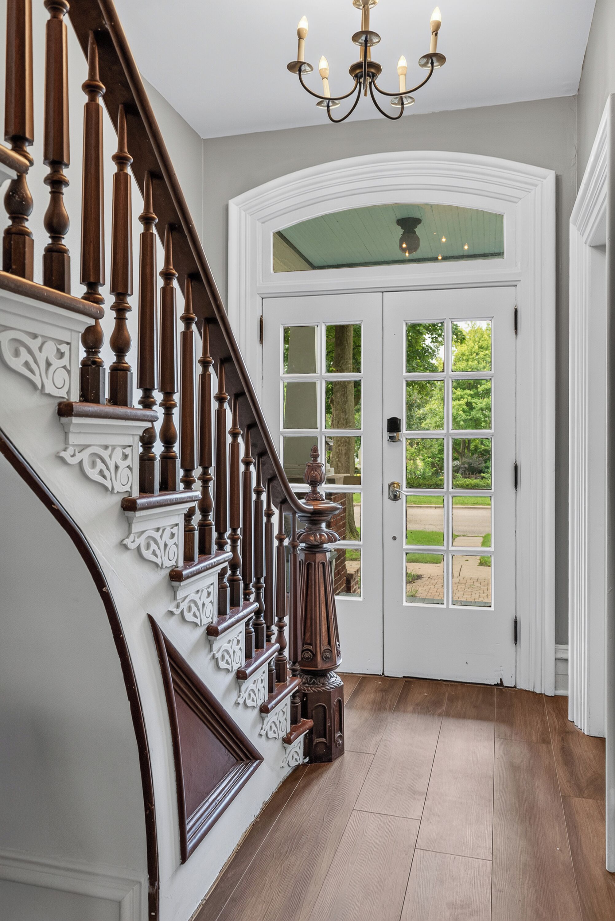 A grand staircase with ornate wood railings leading to a white door with glass panels.