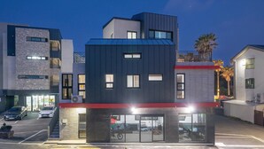 Um edifício moderno com telhado plano, janelas amplas e um detalhe vermelho no andar térreo.