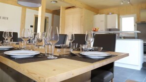 Uma sala de jantar com uma mesa de madeira posta para refeição, rodeada por cadeiras.
