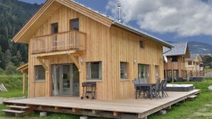 Uma cabana de madeira com varanda, um deck e uma mesa com cadeiras.