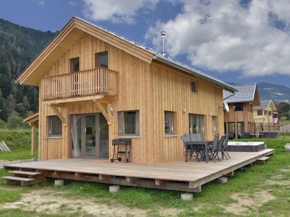 Une cabane en bois dotée d’un balcon, d’une terrasse et d’une table avec des chaises.