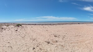 Une vaste plage de sable fin, ouverte et baignée par un ciel dégagé.