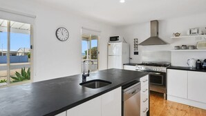 Une cuisine moderne avec un plan de travail noir, des meubles blancs, une cuisinière en acier inoxydable et un four à micro-ondes.