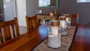 Une table à manger sur laquelle sont posés trois pots en verre contenant ce qui ressemble à des bougies ou de petits récipients, le tout placé sur un set de table en fibres tressées.