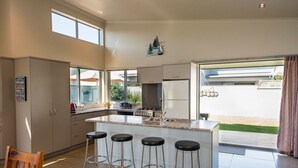 Une cuisine moderne dotée d’un îlot central, de tabourets de bar et offrant une vue sur le jardin arrière.
