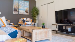 Un salon moderne avec un canapé, une table basse et un téléviseur.