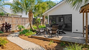 A patio with outdoor furniture, a wooden deck, and a covered seating area. - Stunning backyard oasis nestled between pier/village and beach - SSI Sunshine (St Simons Island)
