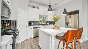 A modern kitchen with white cabinetry, a central island, bar stools, and pendant lighting. - ✵ Casa Blanca✵| Rooftop With Skyline View *  *Game Room* Private Chef (Houston)