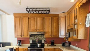 Una cocina con armarios de madera, un lavamanos de acero inoxidable y una cafetera.