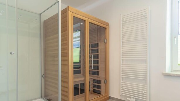 A room with a glass shower enclosure, a wooden wardrobe with glass doors, and a radiator on the wall. - für bis zu 8 Personen mit IR Sauna by Interhome (Eisenerz)