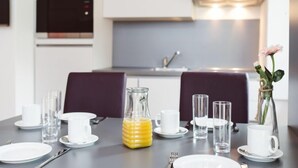 A dining table set with white plates, cups, and a glass pitcher of orange juice.