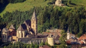 Una cittadina storica con architettura medievale, tra cui una chiesa con una torre imponente e una struttura simile a un castello con numerose torri.