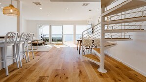Ein geräumiges Zimmer mit Holzboden, heller Möbel und einer Treppe mit Geländer.