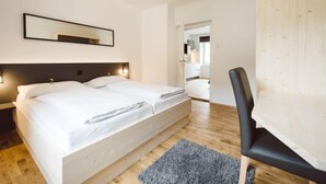 A modern hotel room with a large bed, a desk, and a chair.