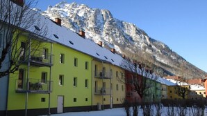 A row of colorful buildings with balconies, set against a backdrop of snow-covered mountains.
