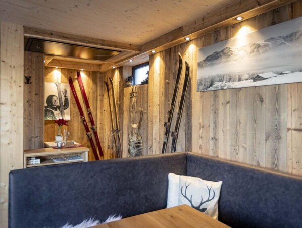 A wooden interior with skis mounted on the wall, a bench, and a table.