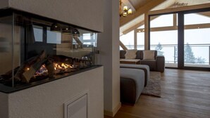 A modern interior with a fireplace, a cozy seating area, and large windows offering a view of the outdoors. - Premium # 01 IR-Sauna&Sprudelpool aussen by Interhome (Pichl)