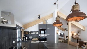 A modern kitchen with dark cabinetry, a central island, and pendant lighting. - Premium # 01 IR-Sauna&Sprudelpool aussen by Interhome (Pichl)