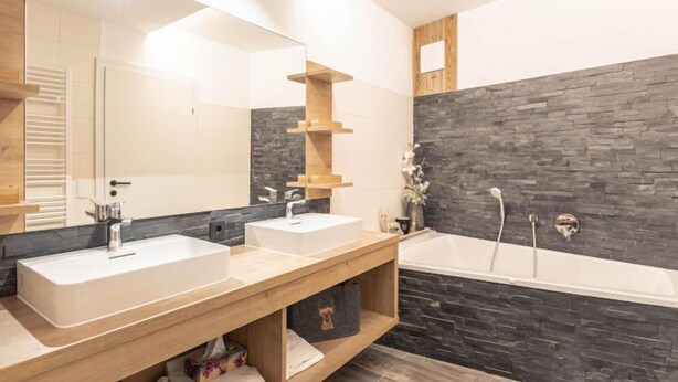 Ein modernes Badezimmer mit zwei Waschbecken, einem großen Spiegel und einer Badewanne.