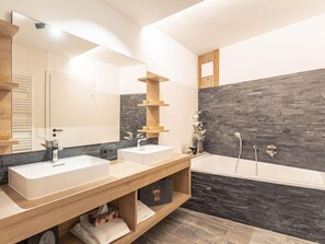 Ein modernes Badezimmer mit zwei Waschbecken, einem großen Spiegel und einer Badewanne.