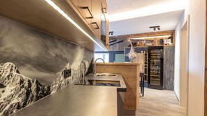 A modern kitchen with a mountain mural, wooden cabinets, and a built-in wine rack. - Superior # 03 Sauna&Sprudelwanne innen by Interhome (Pichl)