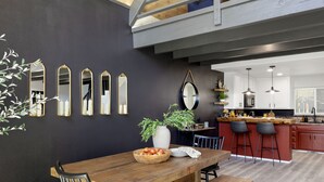 A modern kitchen with dark walls, wooden countertops, and a dining area with a wooden table and chairs.