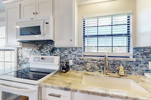 Enjoy cooking in this well-equipped kitchen with a microwave, stainless steel faucet, and sink.