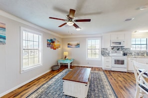 Enjoy meals in the kitchen with a dining table and bench, surrounded by large windows and a ceiling fan.