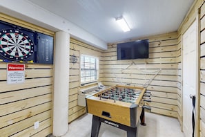 Relax and unwind in this recreational room featuring a foosball table, dartboard, and flat-screen TV.
