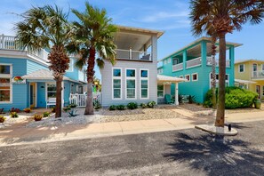 Stunning beachfront property with two-story buildings and balconies, surrounded by palm trees and lush greenery.