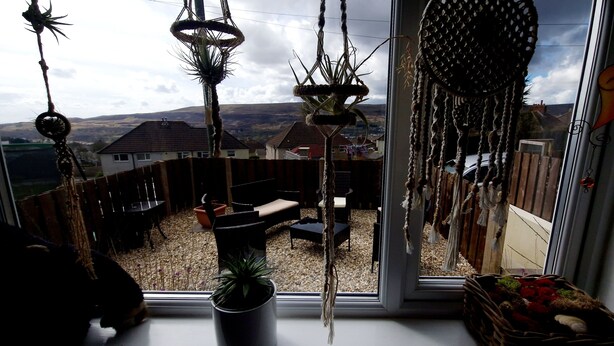 A room with a view of a rural landscape, a wooden fence, and a window with macrame decorations. - Charming 1-bed Maisonette With Mountain View (Pontypool)
