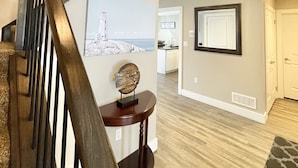 A staircase with a wooden handrail leading to a second floor. A decorative piece is placed on a console table in the hallway.