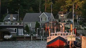 A docked boat near a residential area with houses and a dock.