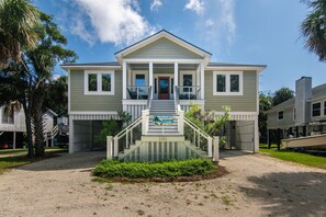 A two-story house with a front porch, a staircase, and a small garden area.