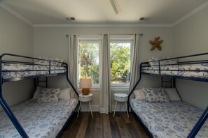 A room with two bunk beds, a small table, and a window with curtains.