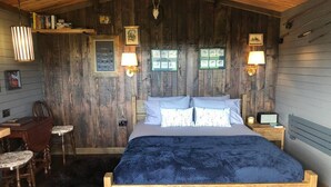 A wooden bedroom with a bed, two bedside lamps, a desk, and a chair. - 1 Bed Cabin in the Magical Galloway Forest Park (Newton Stewart)