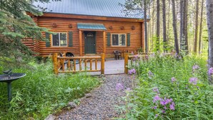 Eine Blockhütte mit Veranda, umgeben von einem Wald.