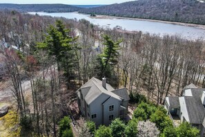 Situated in a serene forest, this two-story house offers a peaceful retreat with a gabled roof and chimney.