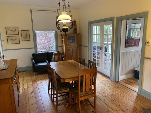 Enjoy meals in this dining area with a table, chairs, and a sofa, offering a view through the glass door to the outdoors.