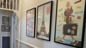 Un pasillo con carteles de viajes enmarcados, un banco de madera y un radiador.