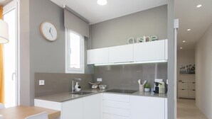 Eine moderne Küche mit weißen Schränken, einem eingebauten Backofen und einer Arbeitsplatte mit Küchengeräten.
